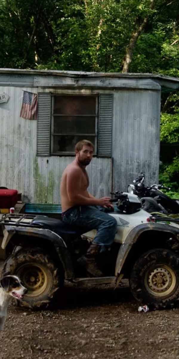 Guy on ATV with dog in front of trailer