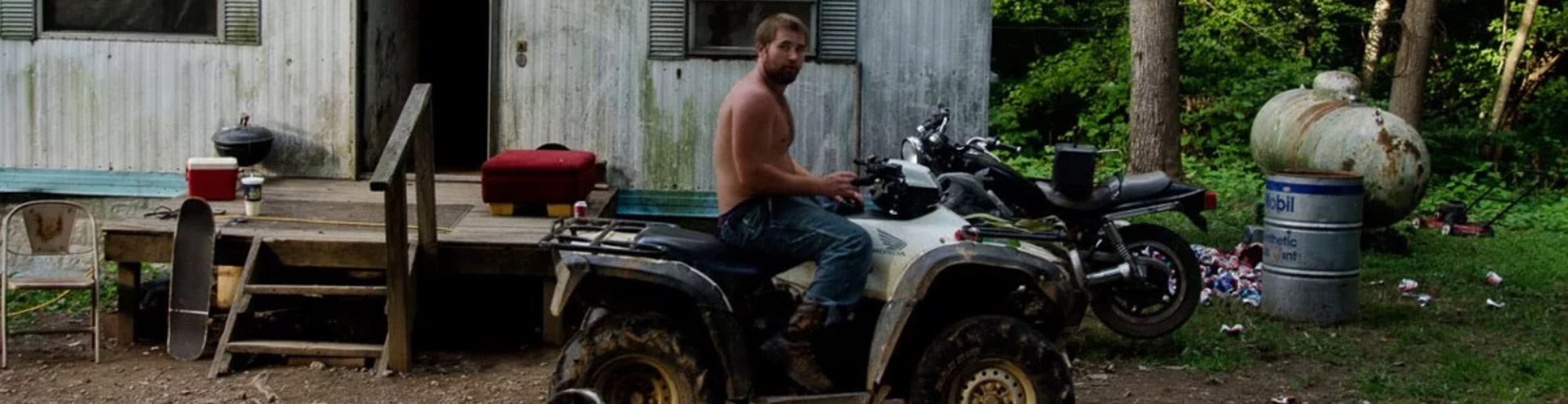 Guy on ATV with dog in front of trailer